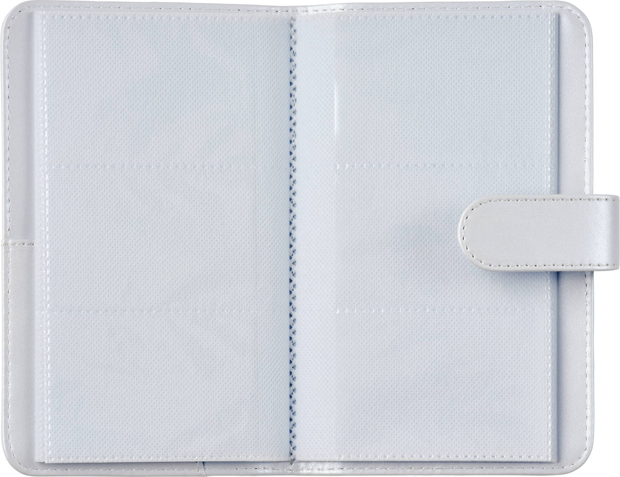 Un album photo blanc ouvert avec des fentes d'insertion vides et une fermeture à sangle.