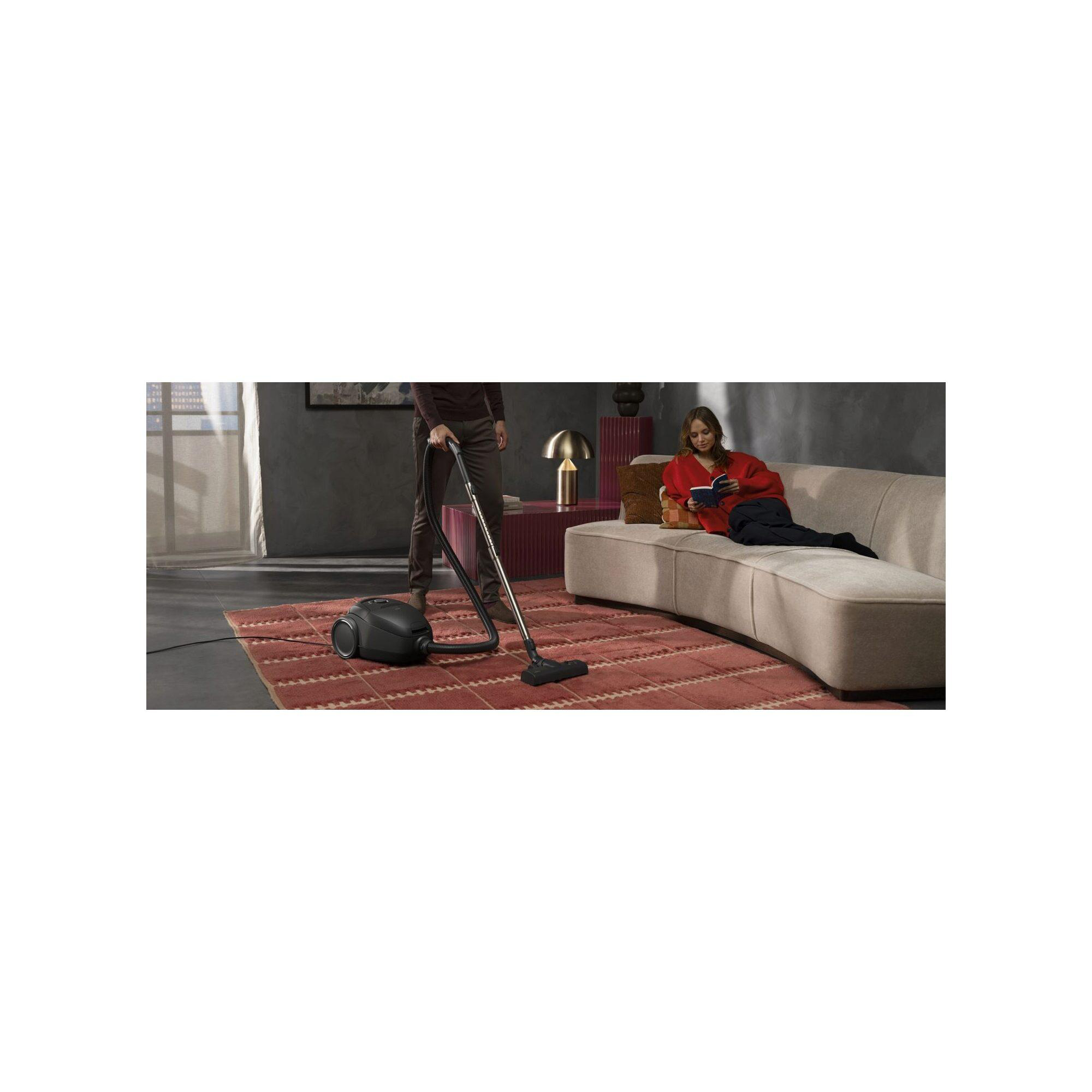 Mann saugt Teppich, Frau liest auf Sofa. Modernes Wohnzimmer.