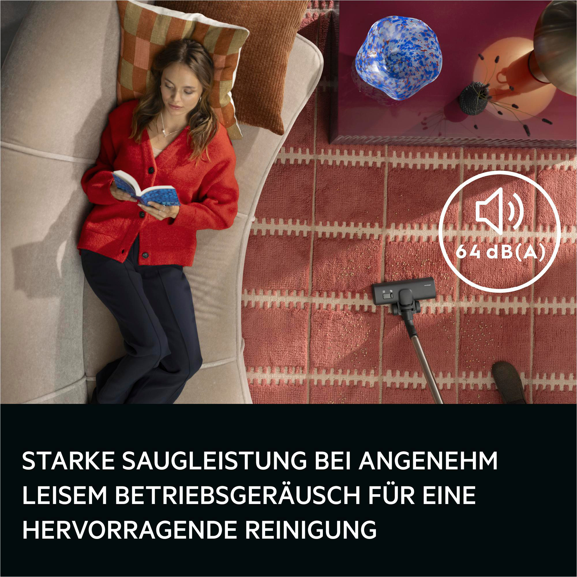 Frau liest auf Sofa, Staubsauger auf Teppich mit Lautstärkesymbol 64 dB(A).
