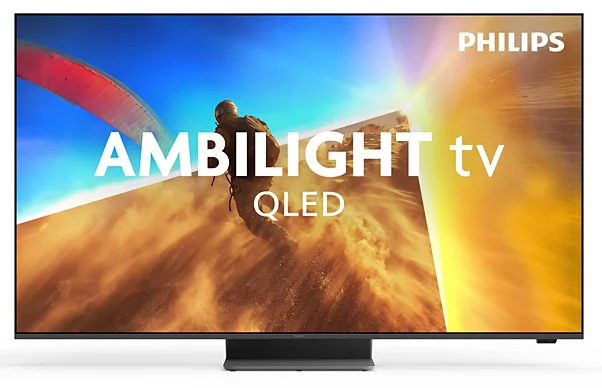 Ein Mann mit Gleitschirm fliegt über eine sandige Landschaft. Philips Ambilight TV QLED.