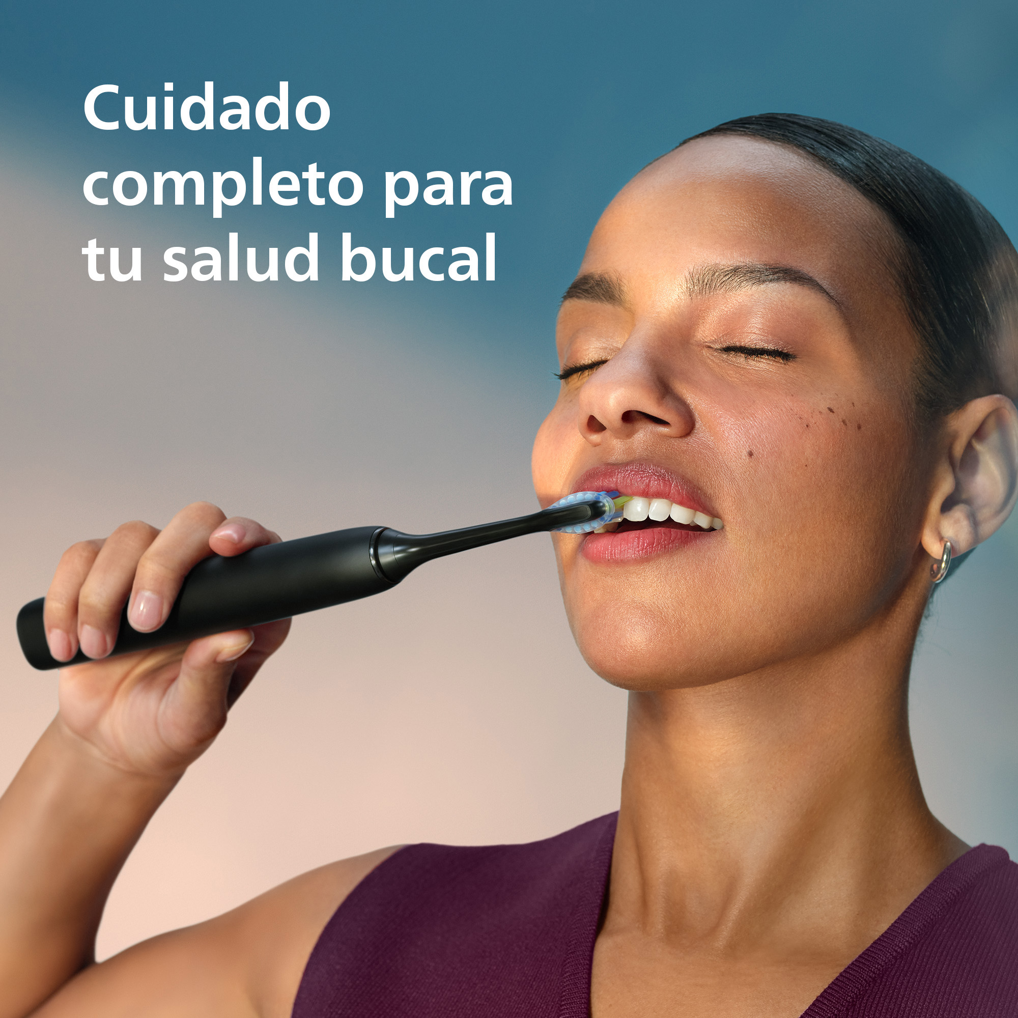 Mujer cepillándose los dientes con cepillo eléctrico negro, ojos cerrados.
