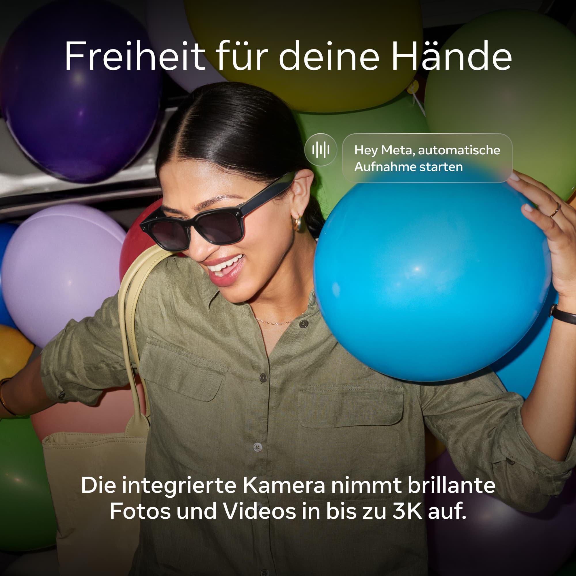 Eine Frau mit Sonnenbrille hält einen blauen Ballon vor vielen bunten Ballons.