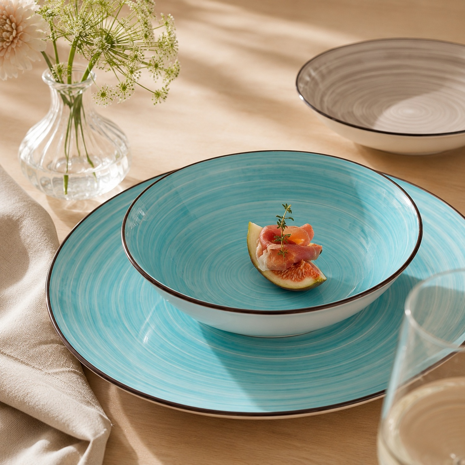 Piatti turchesi con cibo e fiori su tavolo di legno.