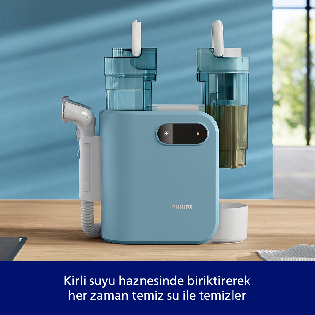 Ahşap masa üzerinde su tankları ve püskürtme başlığı olan açık mavi bir cihaz.