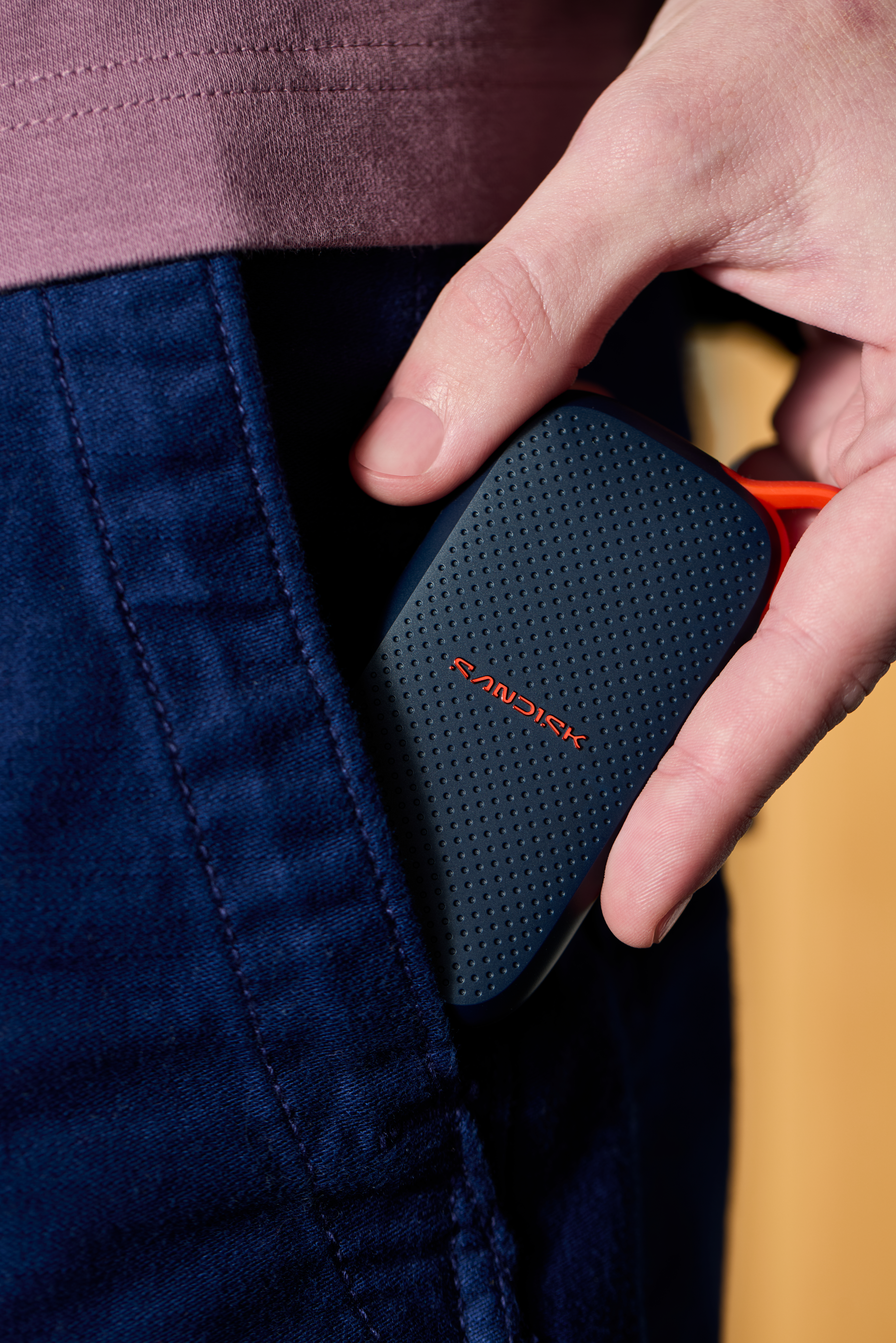 Sandisk SSD wird in eine blaue Jeanstasche gesteckt.