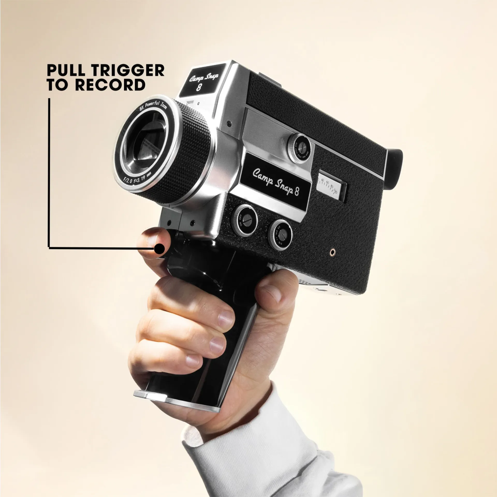 Kézzel tartott ezüst és fekete Camp Snap 8 kamera. A szöveg 'PULL TRIGGER TO RECORD'.