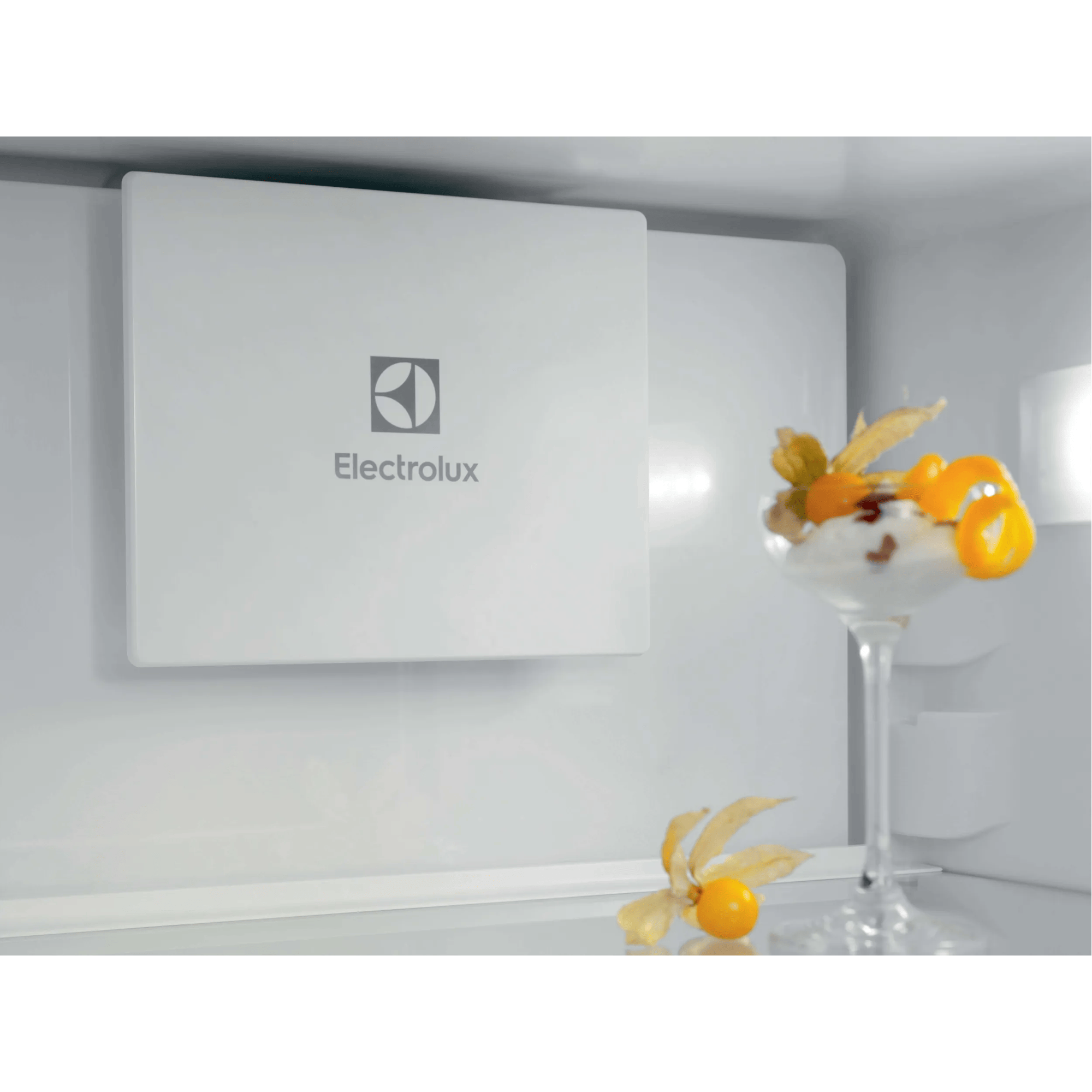 Logo Electrolux na białym panelu w lodówce obok kieliszka deseru.
