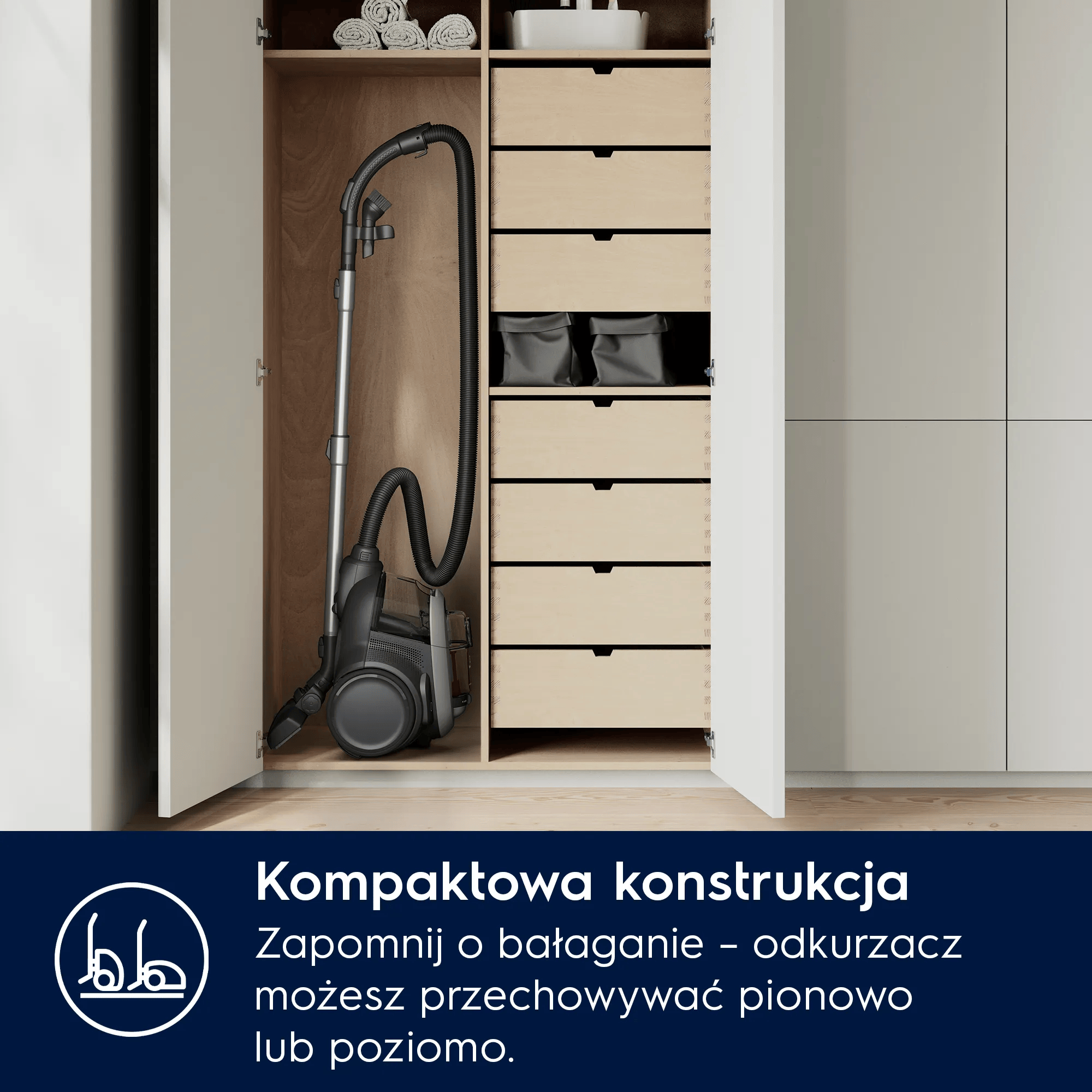 Odkurzacz stoi w otwartej szafce obok szuflad. Ręczniki na górze.