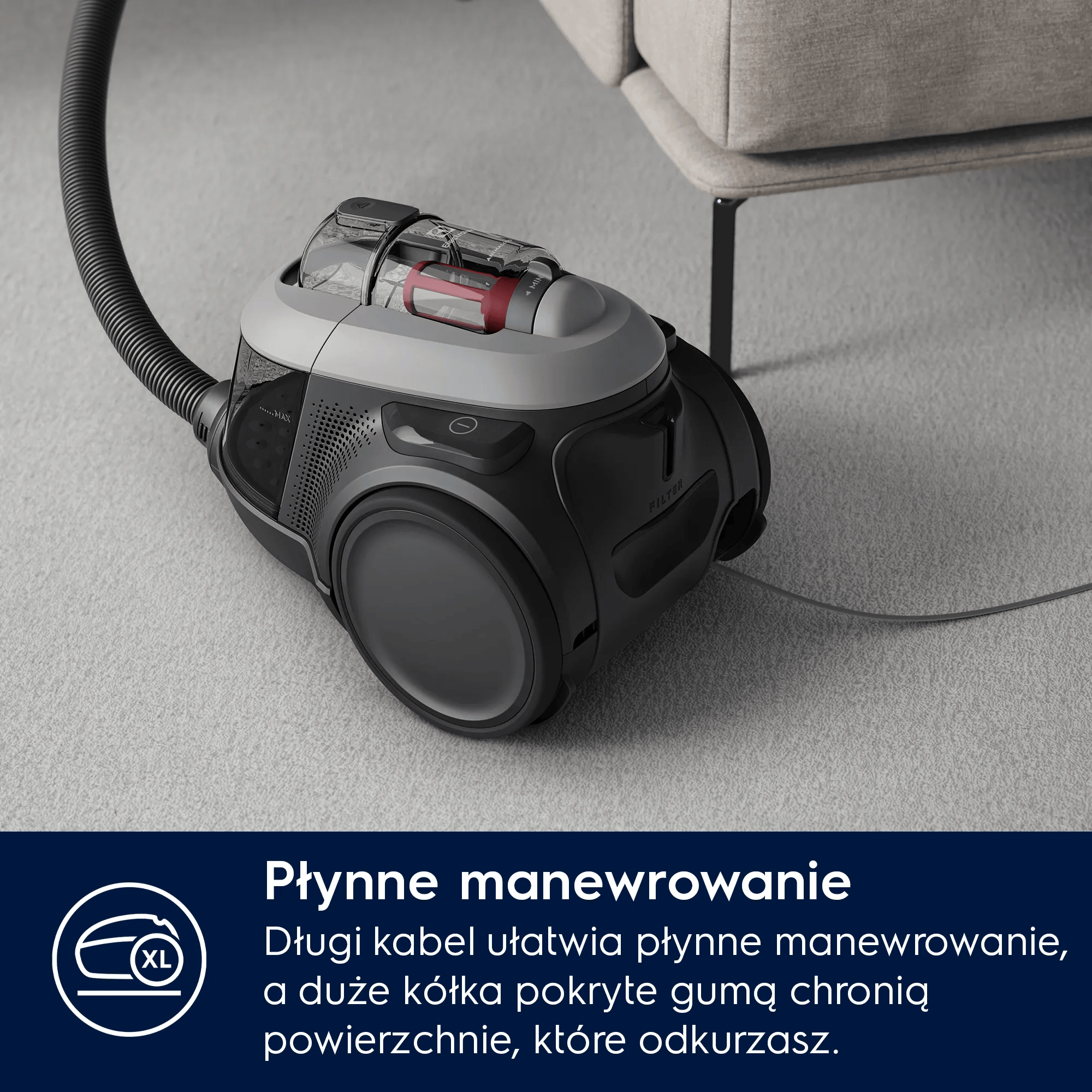 Czarny odkurzacz z wężem na dywanie obok sofy.