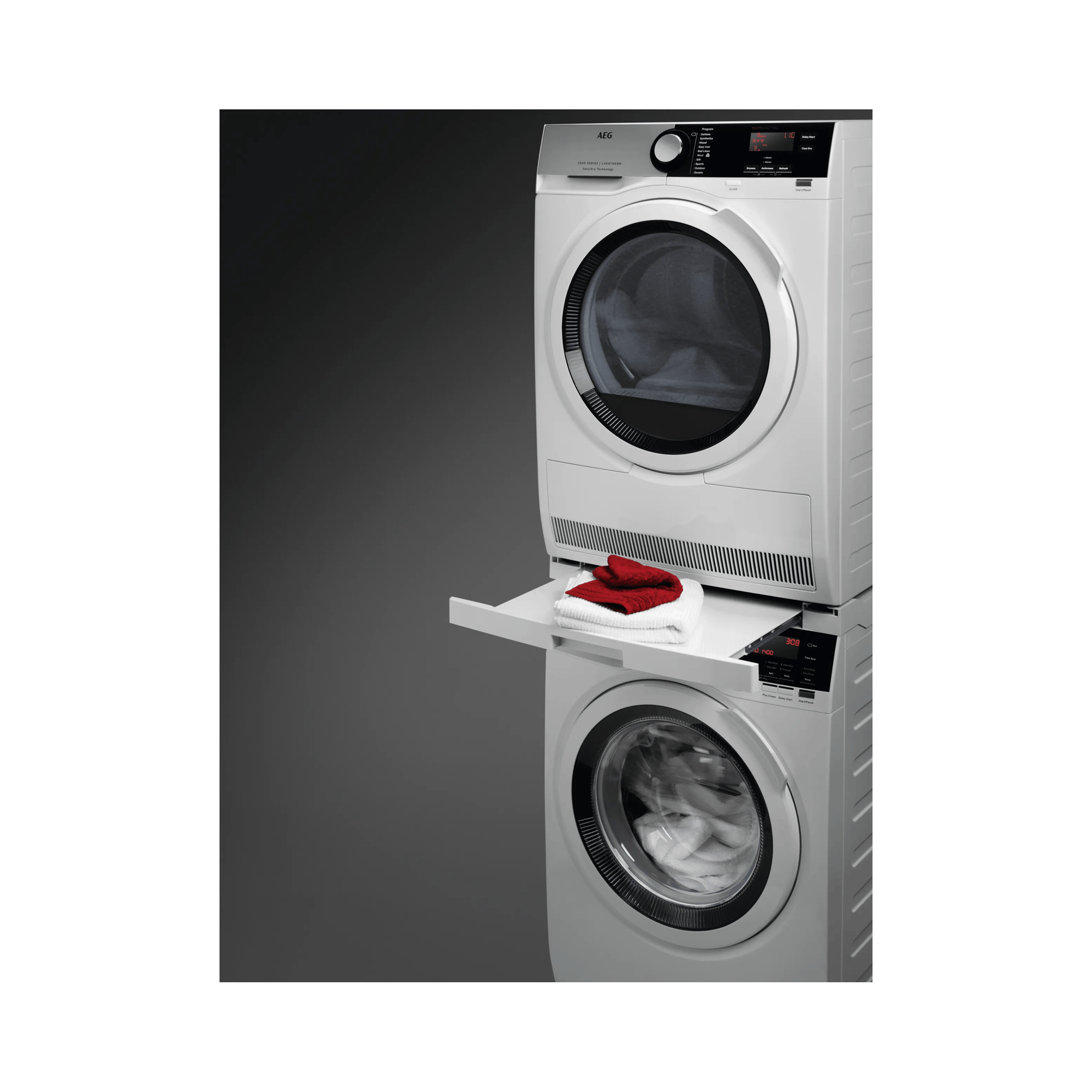 Lave-linge et sèche-linge AEG blancs empilés avec des serviettes sur une étagère.