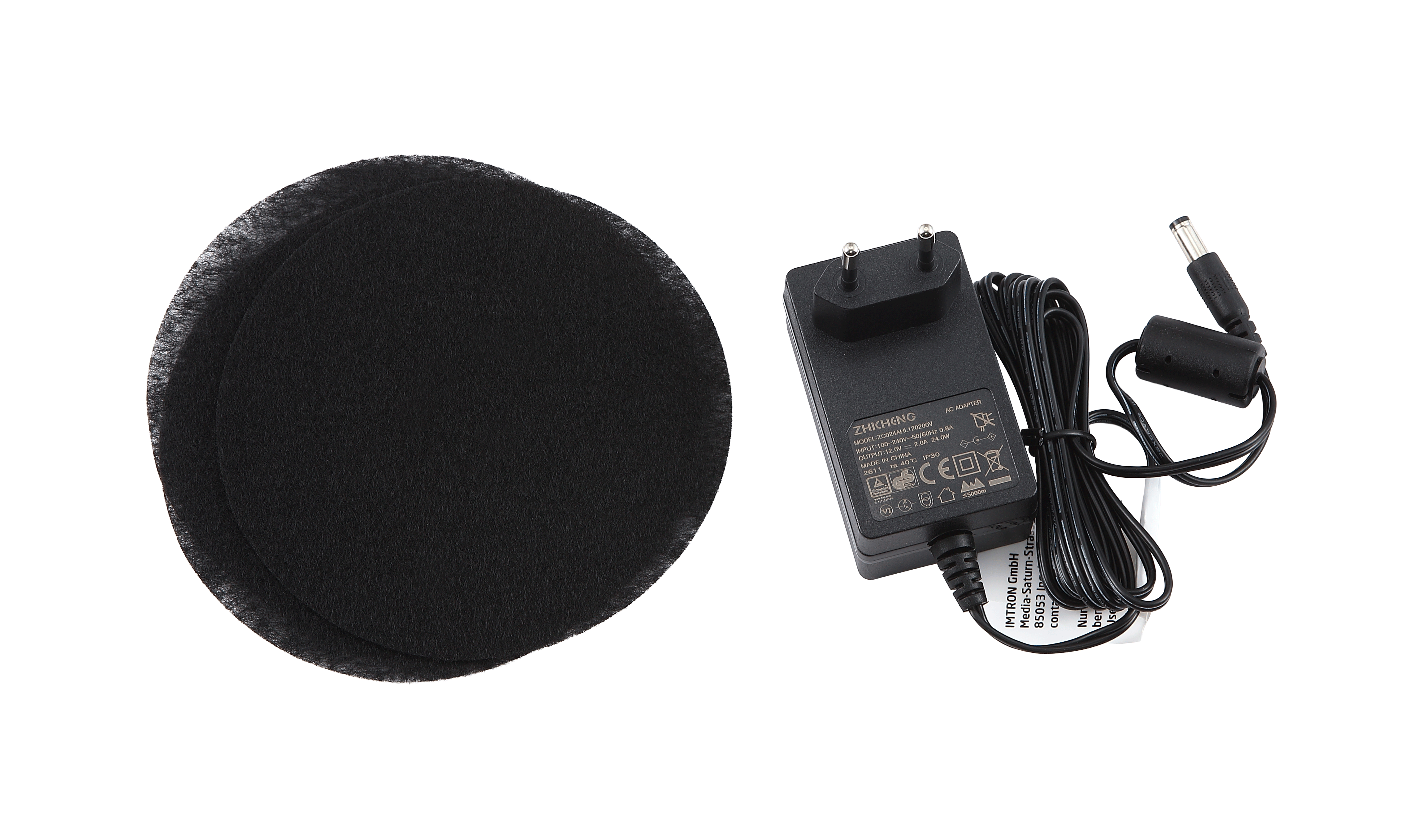 Schwarzer Netzadapter und zwei runde, schwarze Filter auf schwarzem Hintergrund.