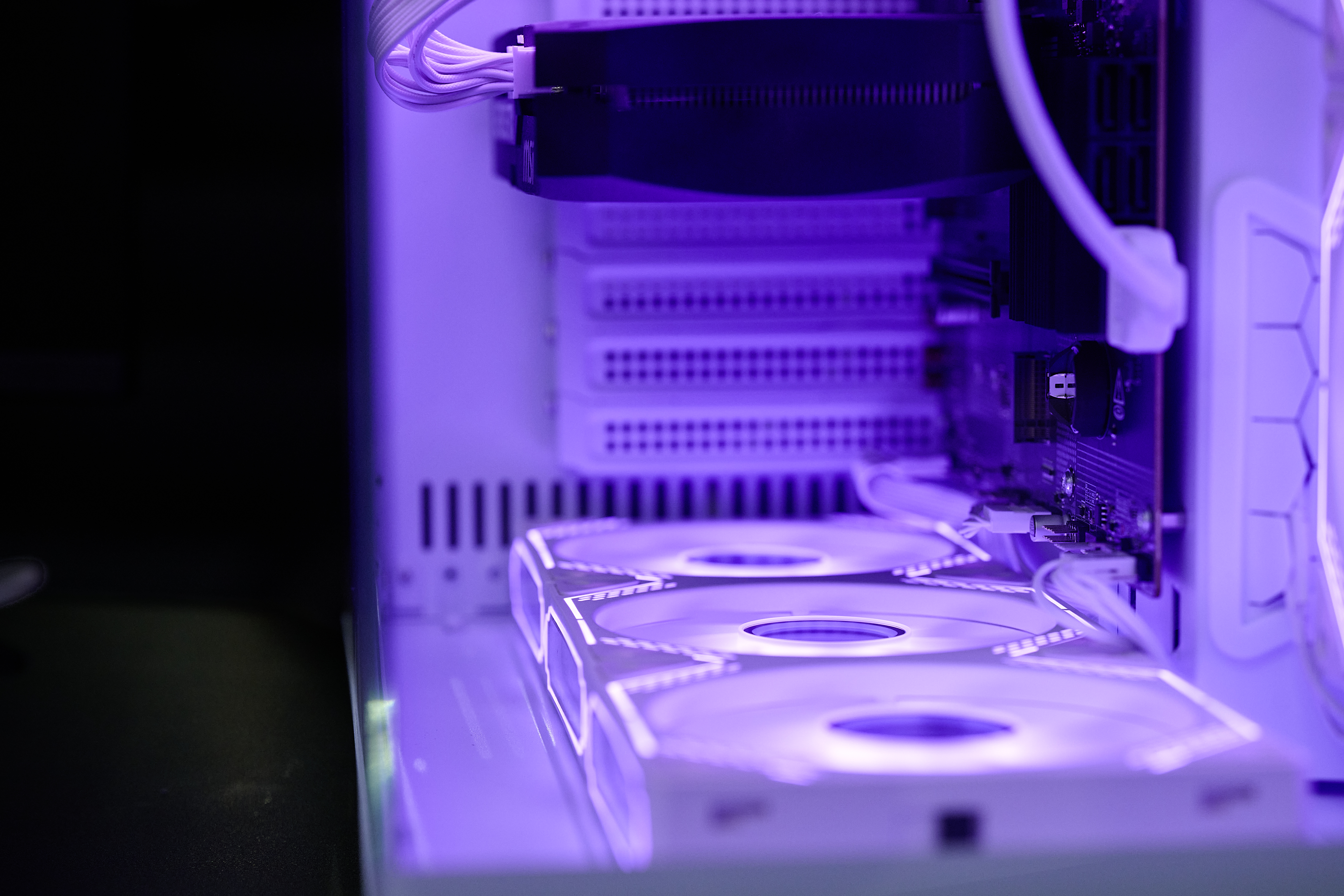 Ein Computergehäuse mit lila Beleuchtung. Lüfter sind vorne, Hauptplatine hinten.