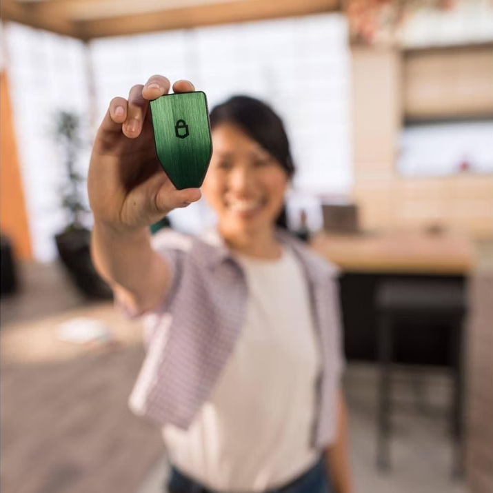 Une femme tient un porte-clés vert avec un symbole de serrure.