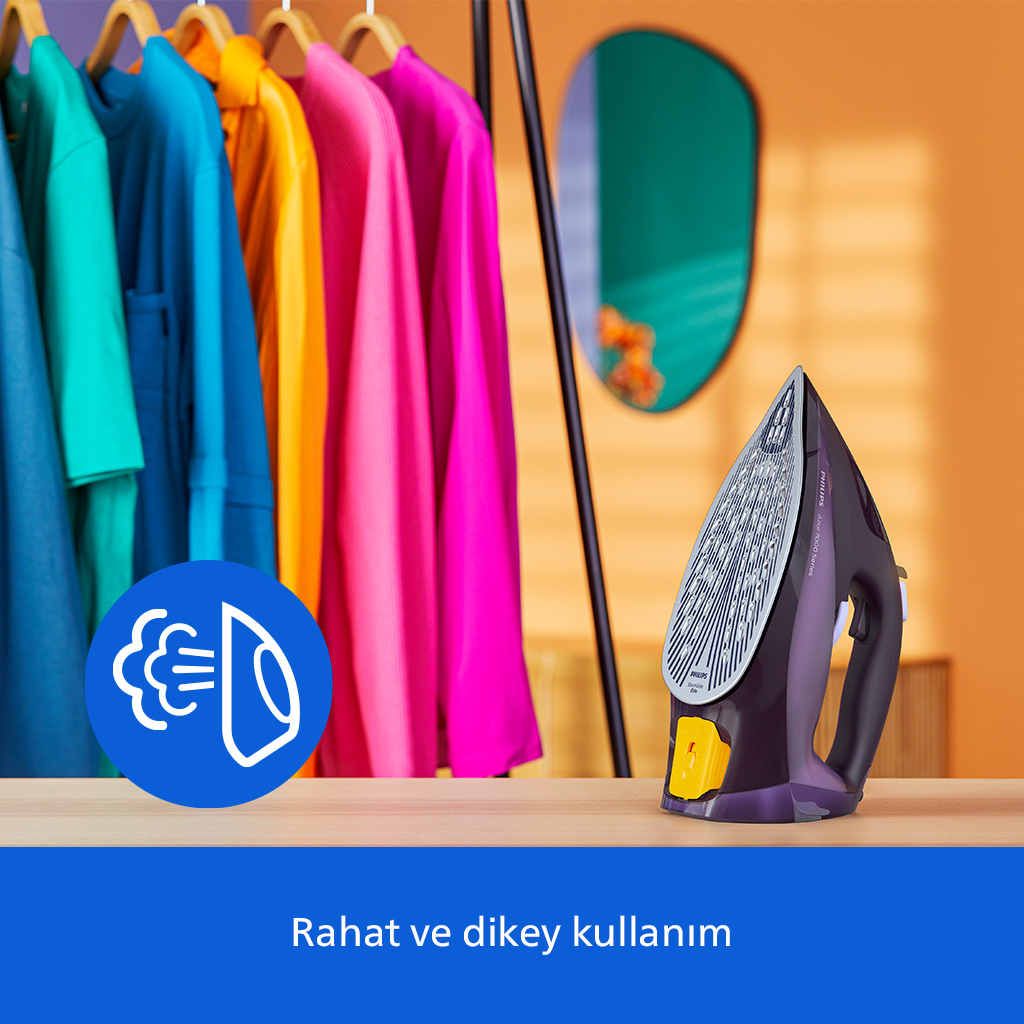 Mor bir ütü, askılardaki renkli giysilerin önünde ahşap bir masada duruyor.