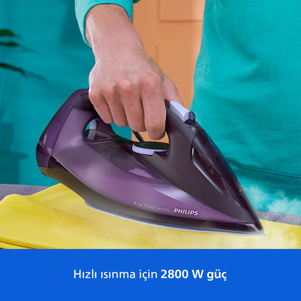 Bir el, sarı kumaşın üzerinde mor bir buharlı ütü tutuyor.