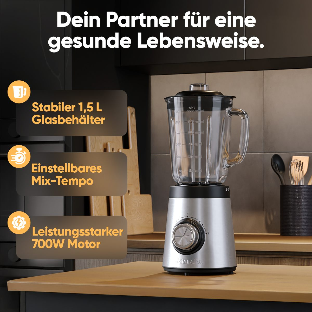 Ein silberner Standmixer mit Glasbehälter steht auf einer Holzoberfläche.