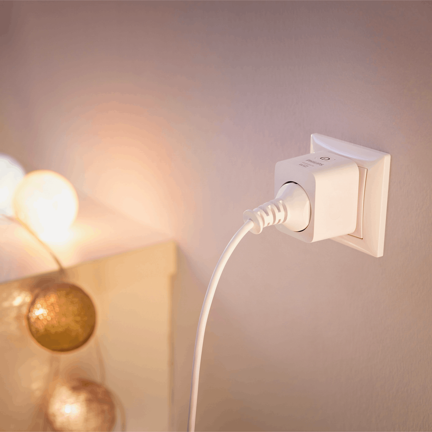 Un enchufe inteligente Philips Hue blanco está enchufado a una toma de pared.