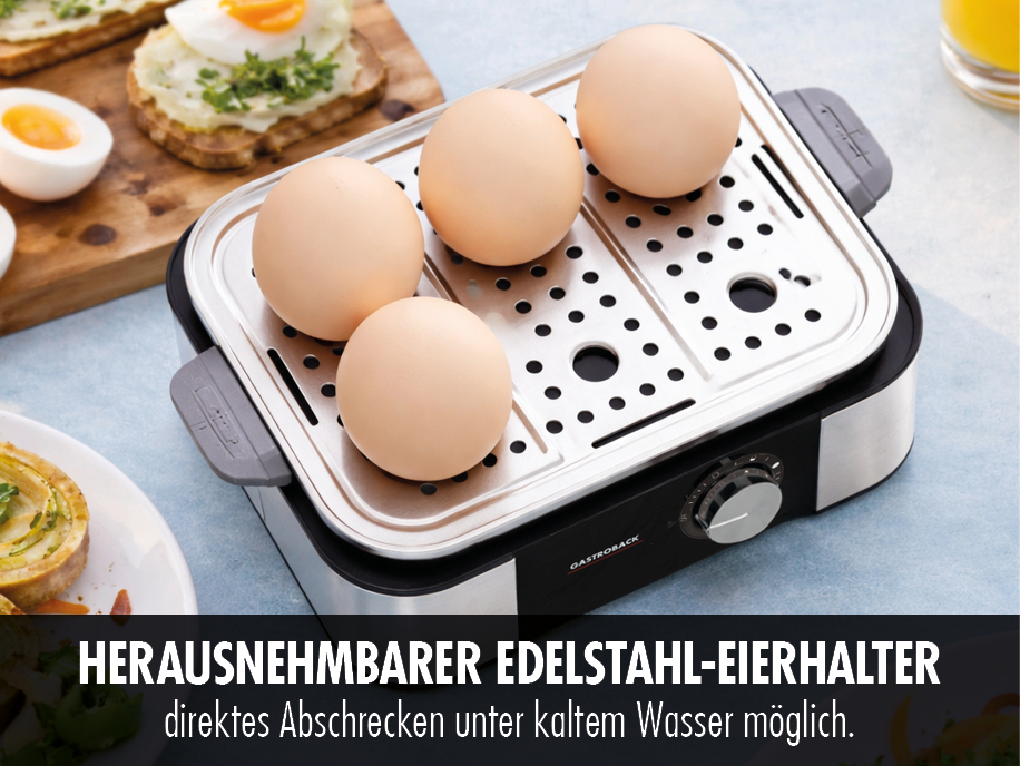 Vier beige Eier in einem silbernen Eierkocher mit Toast und Gebäck im Hintergrund.