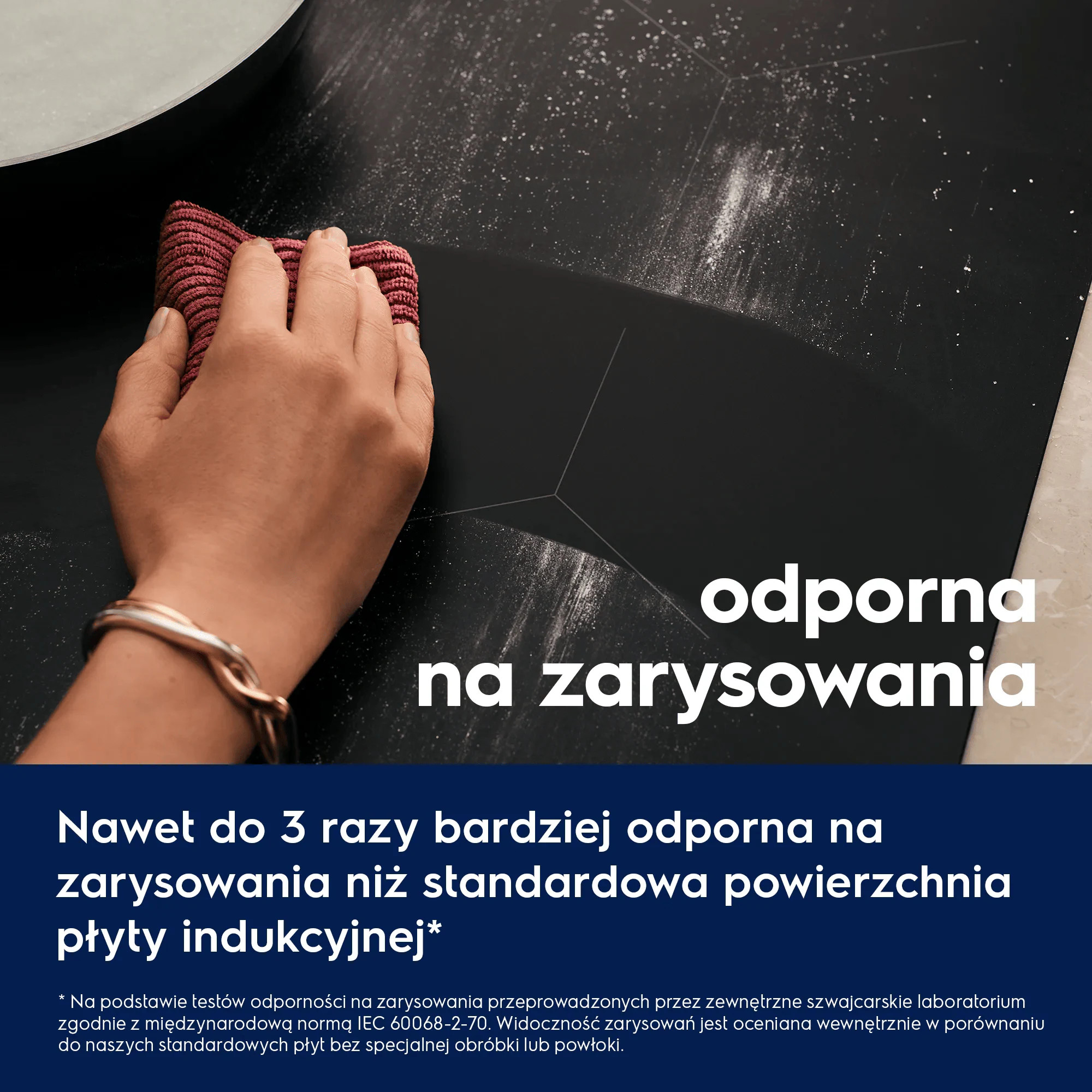 Ręka trzymająca czerwony materiał czyści czarną powierzchnię z białymi drobinkami.