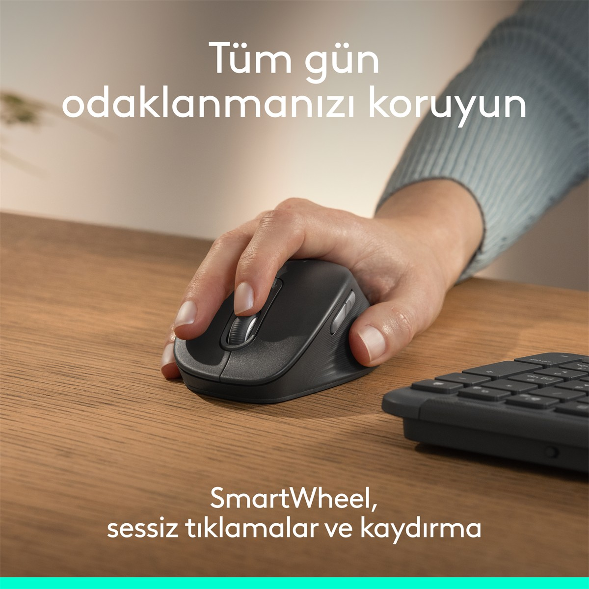 Bir el, klavyenin yanında ahşap bir masada siyah fare kullanıyor.