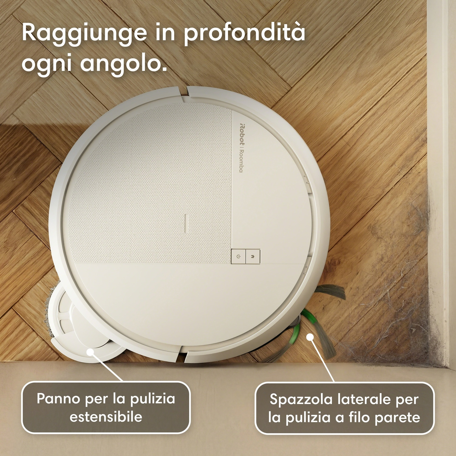 Un robot aspirapolvere bianco pulisce un angolo di parquet con polvere accumulata.
