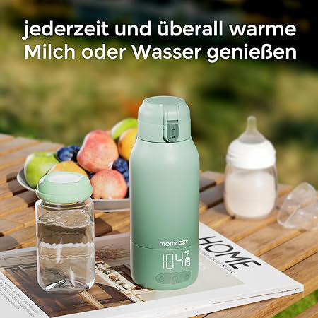 Grüne Thermoskanne mit digitaler Anzeige neben einer Karaffe und Fruchtschale.