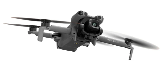 Szara dron DJI Mini 3 Pro z obracającymi się śmigłami na białym tle.