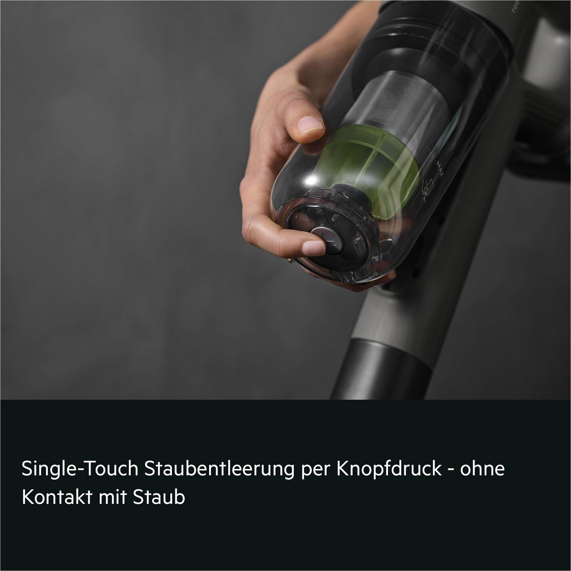 Eine Hand drückt einen Knopf am Staubbehälter eines Staubsaugers.
