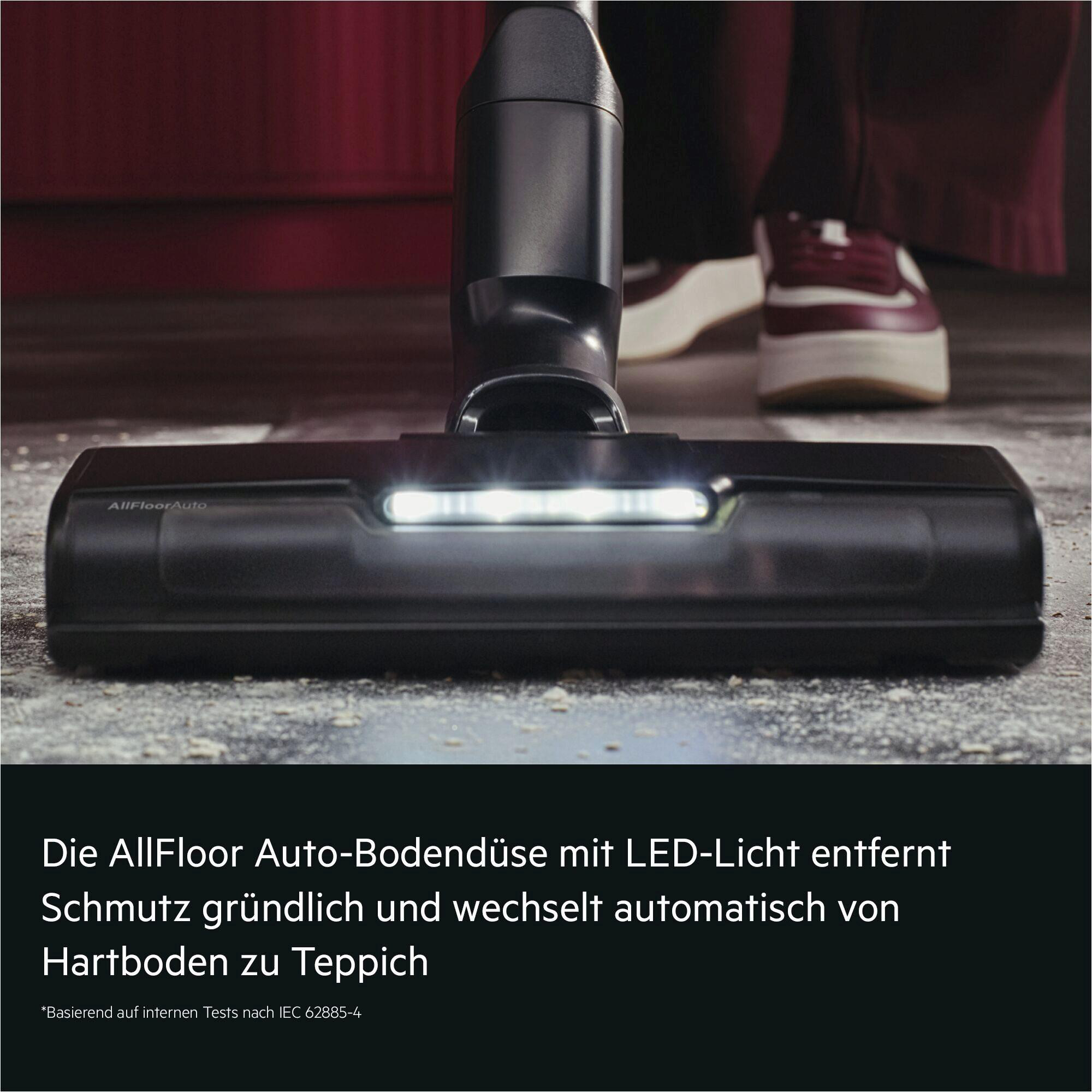Dunkle Bodendüse mit LED-Licht auf schmutzigem Boden, Person in roten Schuhen.