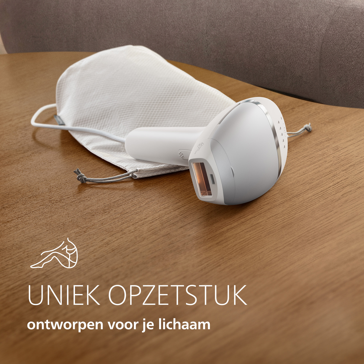 Un appareil blanc d'épilation IPL repose sur une table en bois à côté de son sac de rangement blanc.