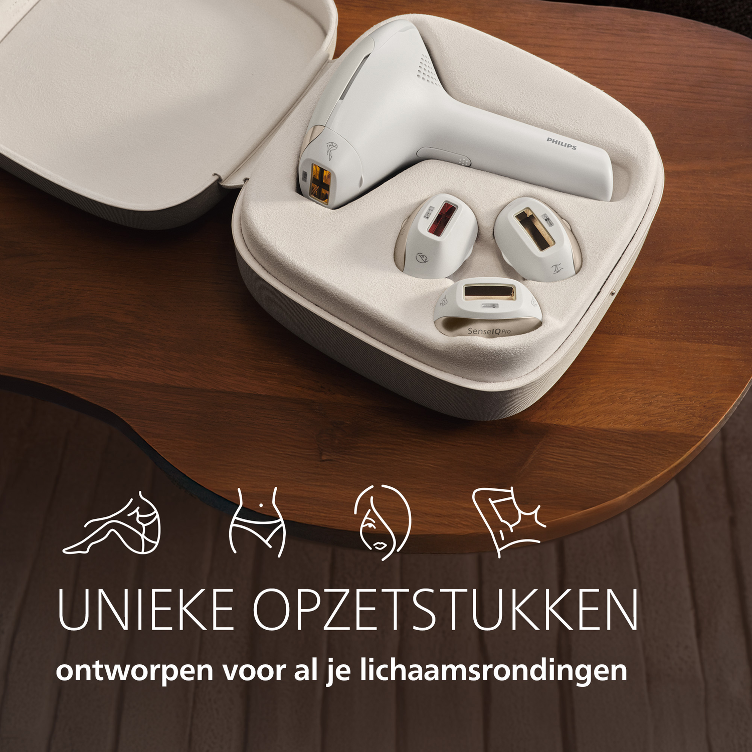 Een wit Philips ontharingsapparaat met opzetstukken in een grijze koffer op een houten tafel.