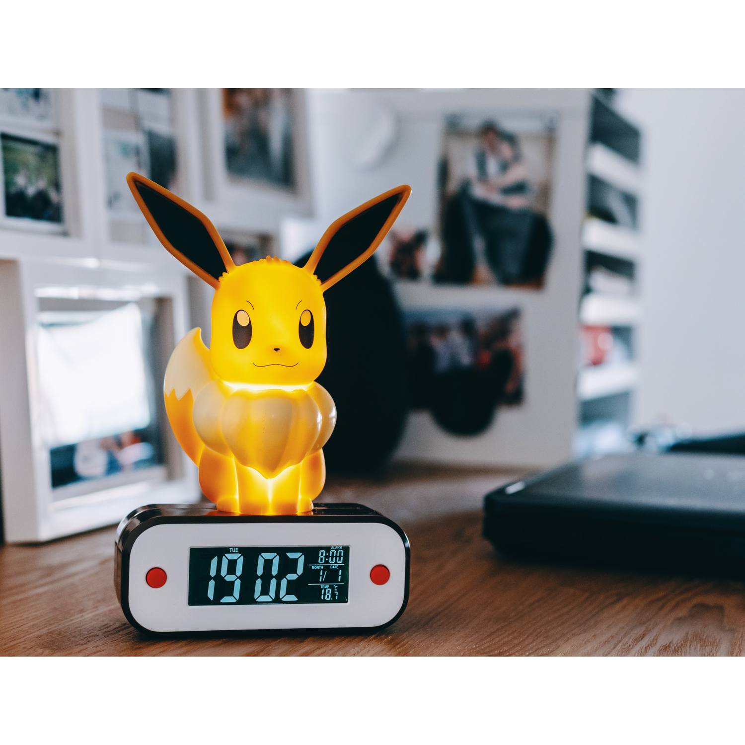 Een gloeiend gele Eevee Pokémon figuur zit bovenop een digitale wekker met de tijd 19:02.