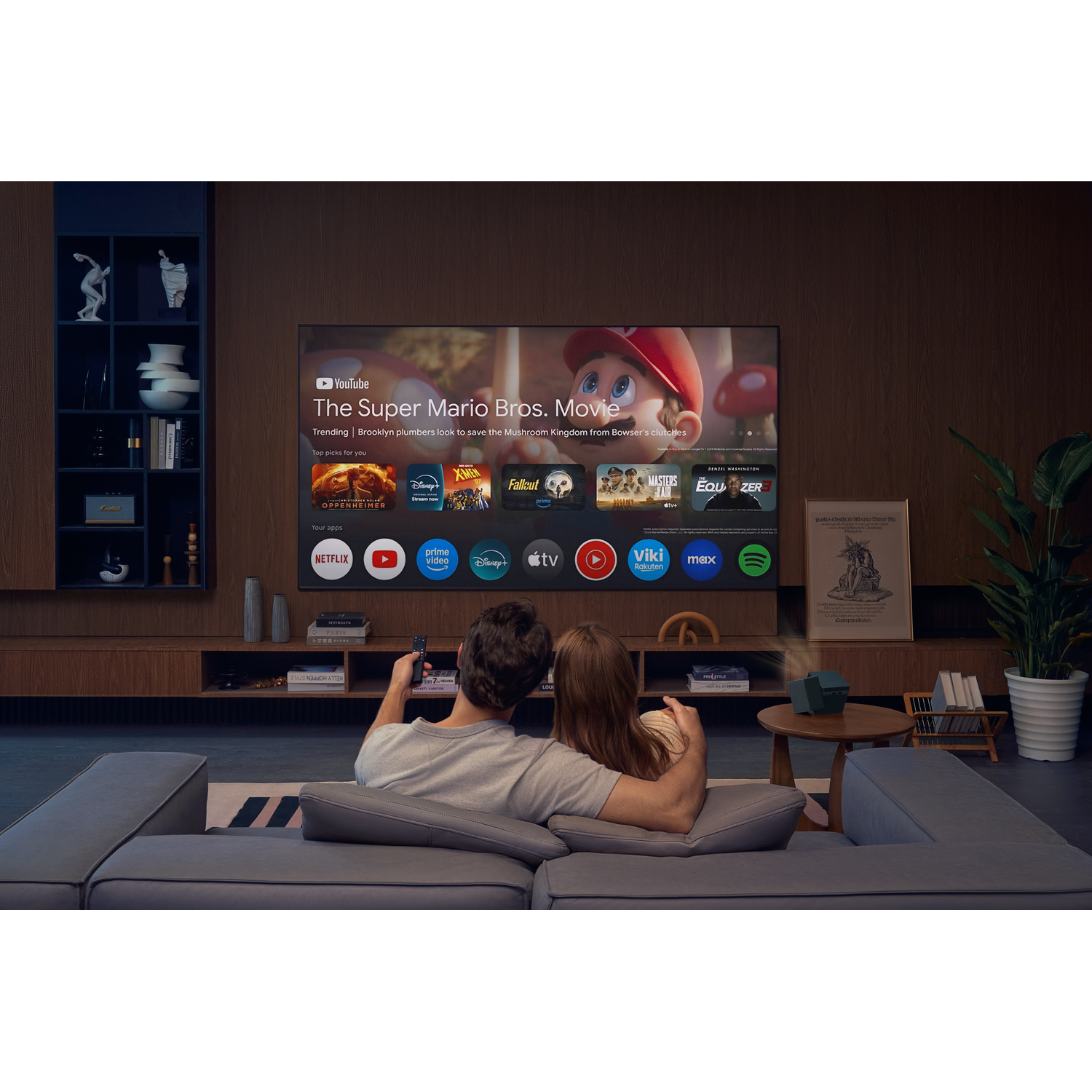 Un couple assis sur un canapé regarde un film sur une smart TV affichant des applications comme YouTube et Netflix.