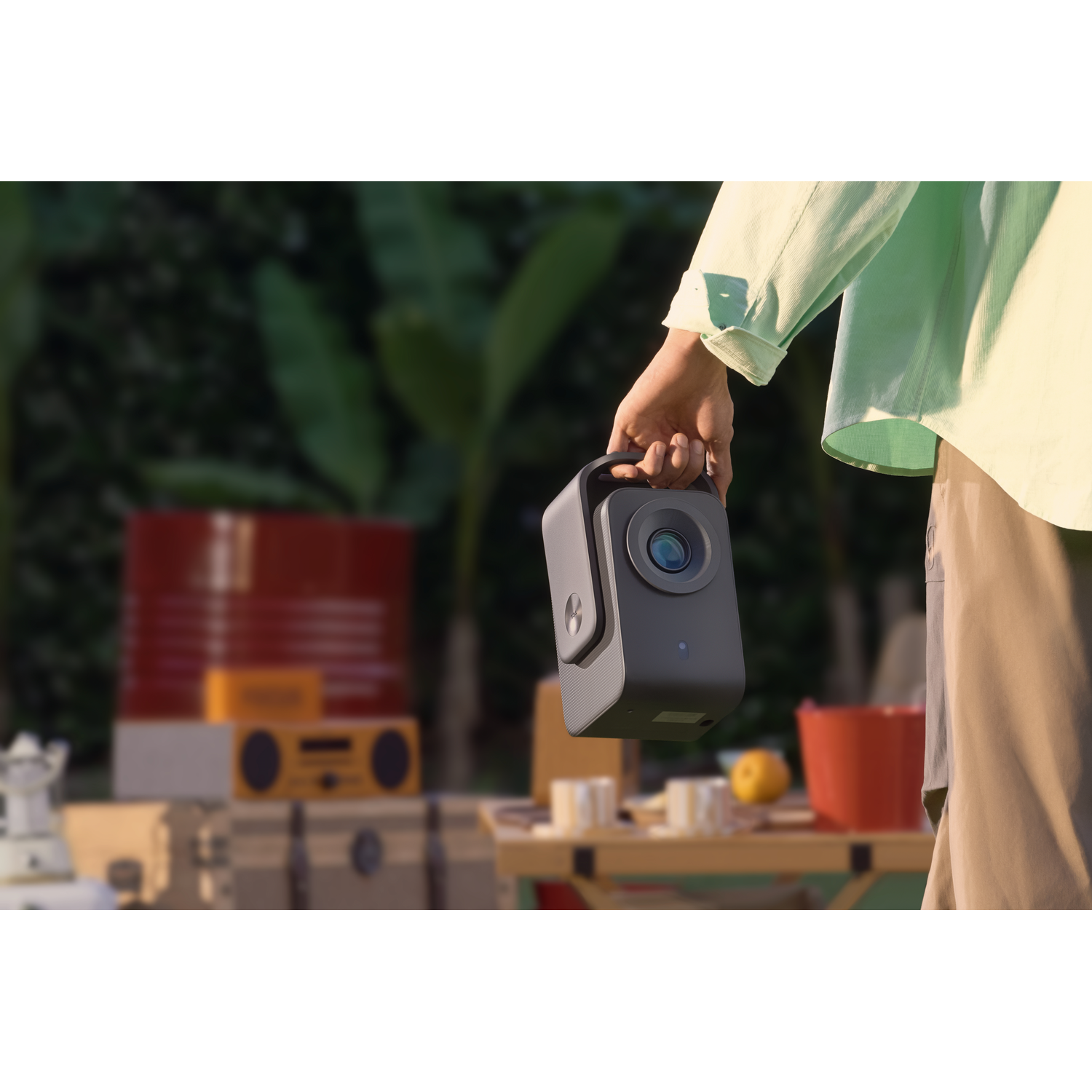 Personne tenant un projecteur gris à l'extérieur avec un arrière-plan flou.