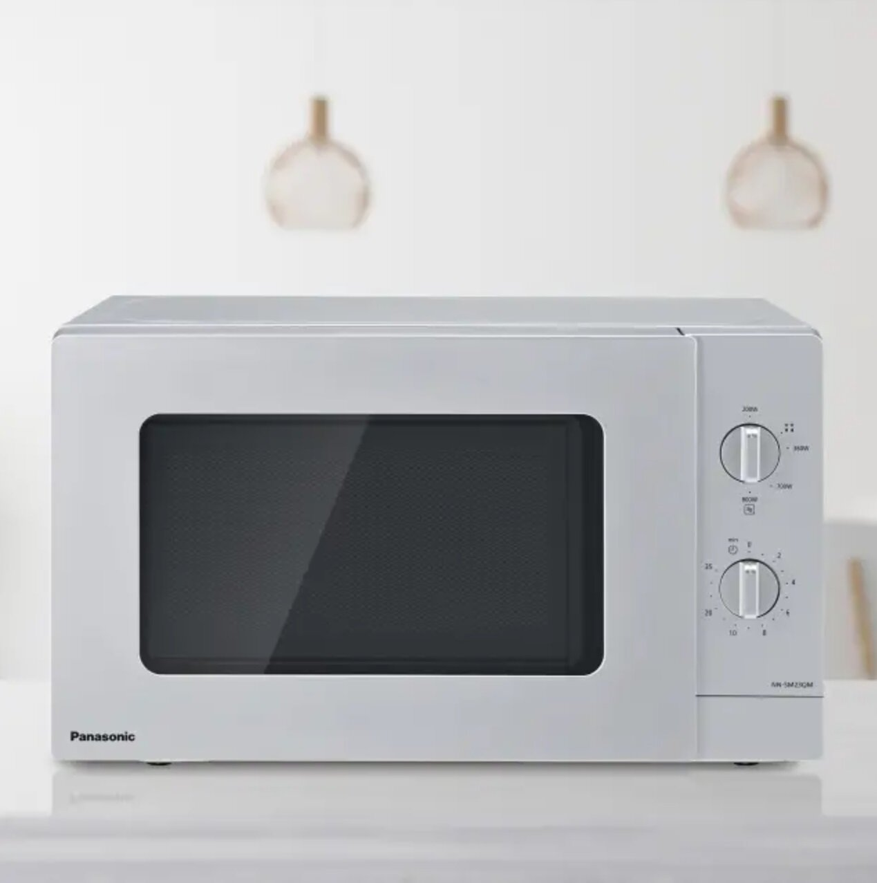 Biała kuchenka mikrofalowa Panasonic z czarnymi drzwiami i dwoma pokrętłami.