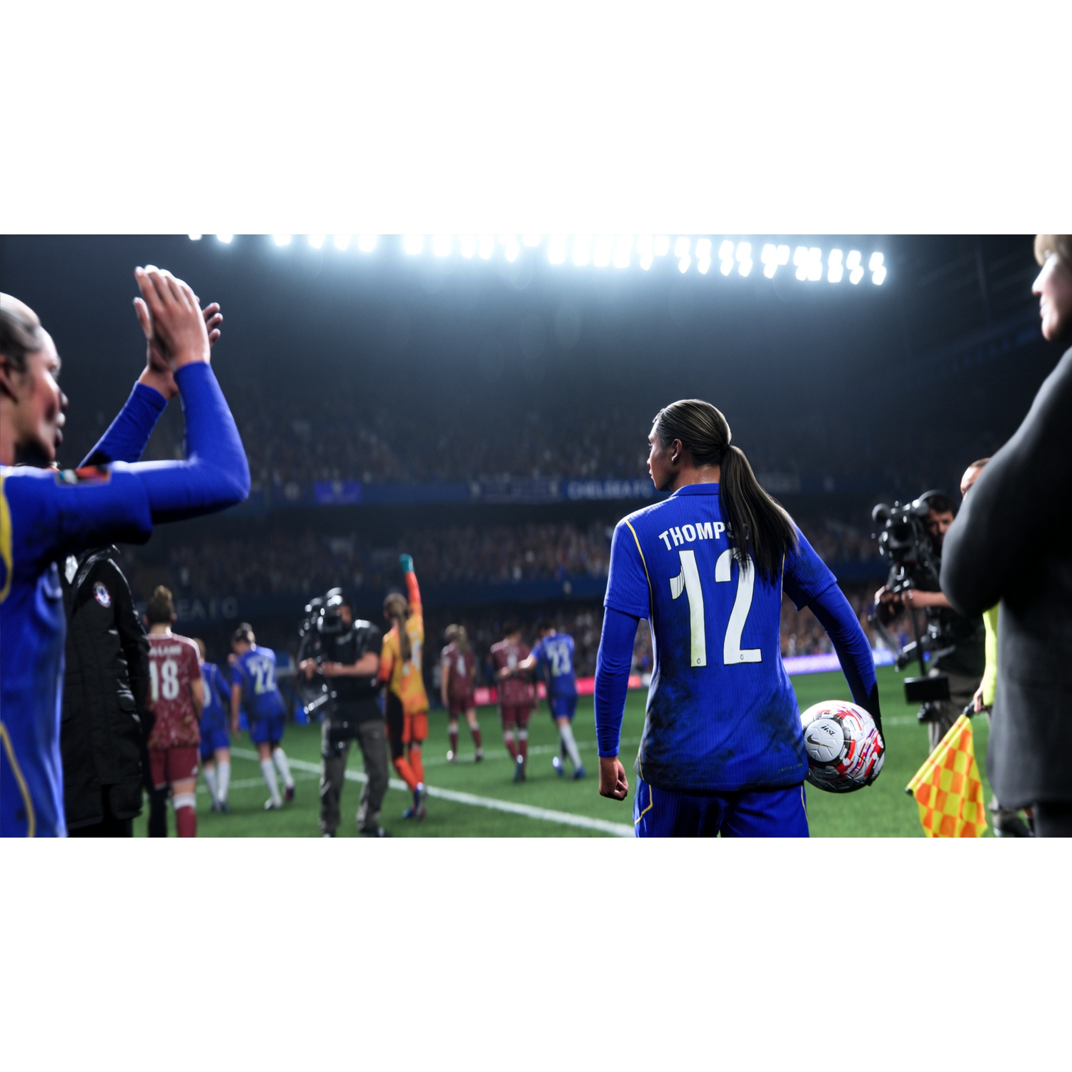 Soccer player in blue jersey #12 holds ball. Teammates and crowd in background.