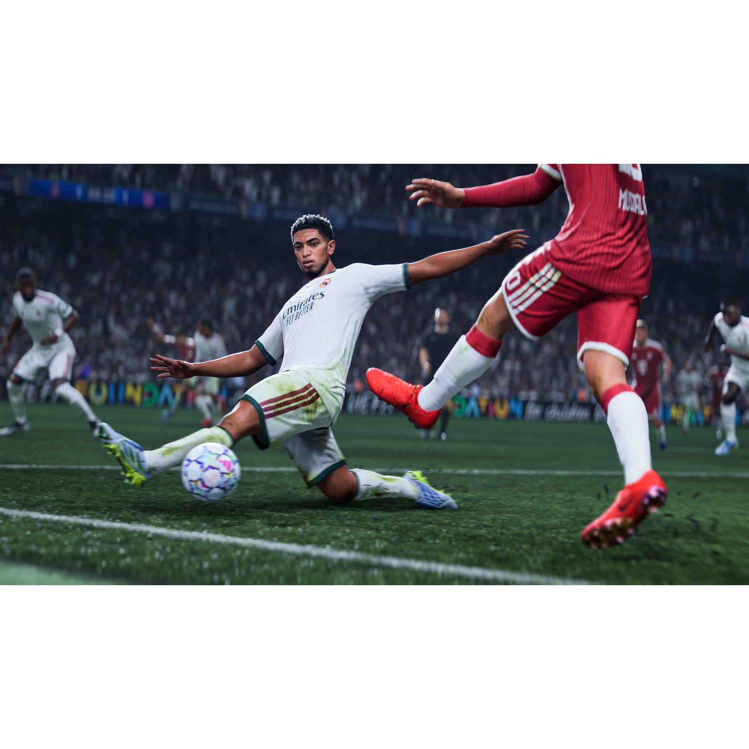 Soccer player in white kit slides on grass, ball nearby.