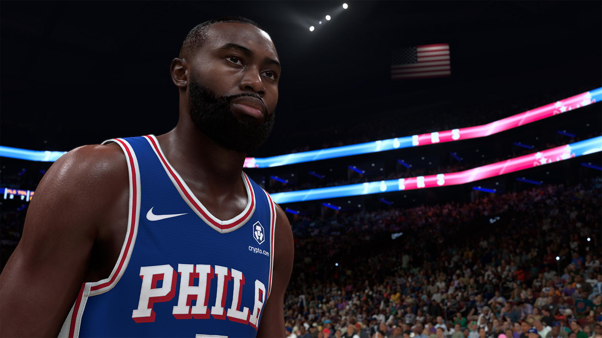 Ein Basketballspieler in einem blauen Philadelphia-Trikot steht im Vordergrund. Im Hintergrund sind Zuschauer und eine amerikanische Flagge zu sehen.