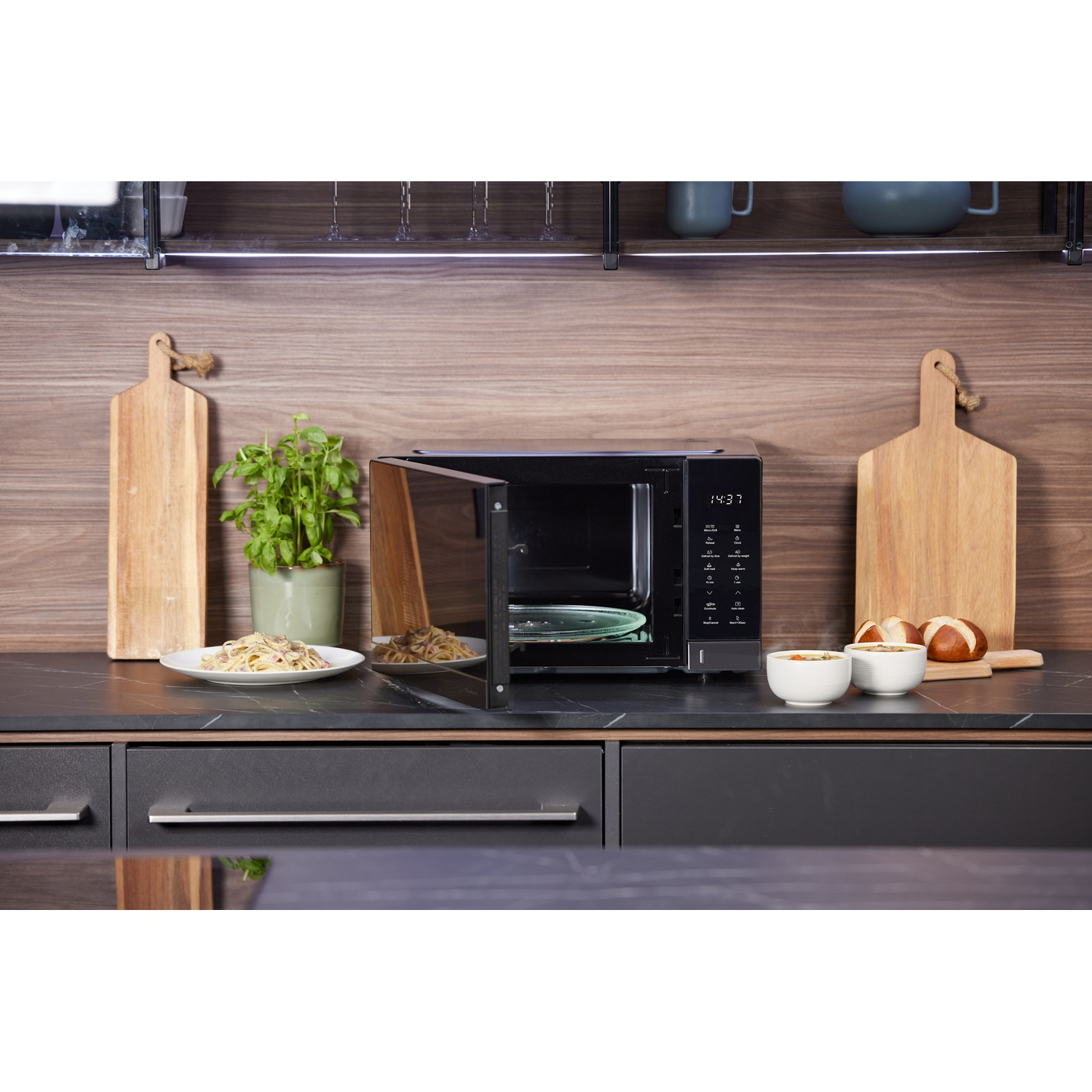 Cucina moderna con microonde aperto, pasta, zuppa e pane.
