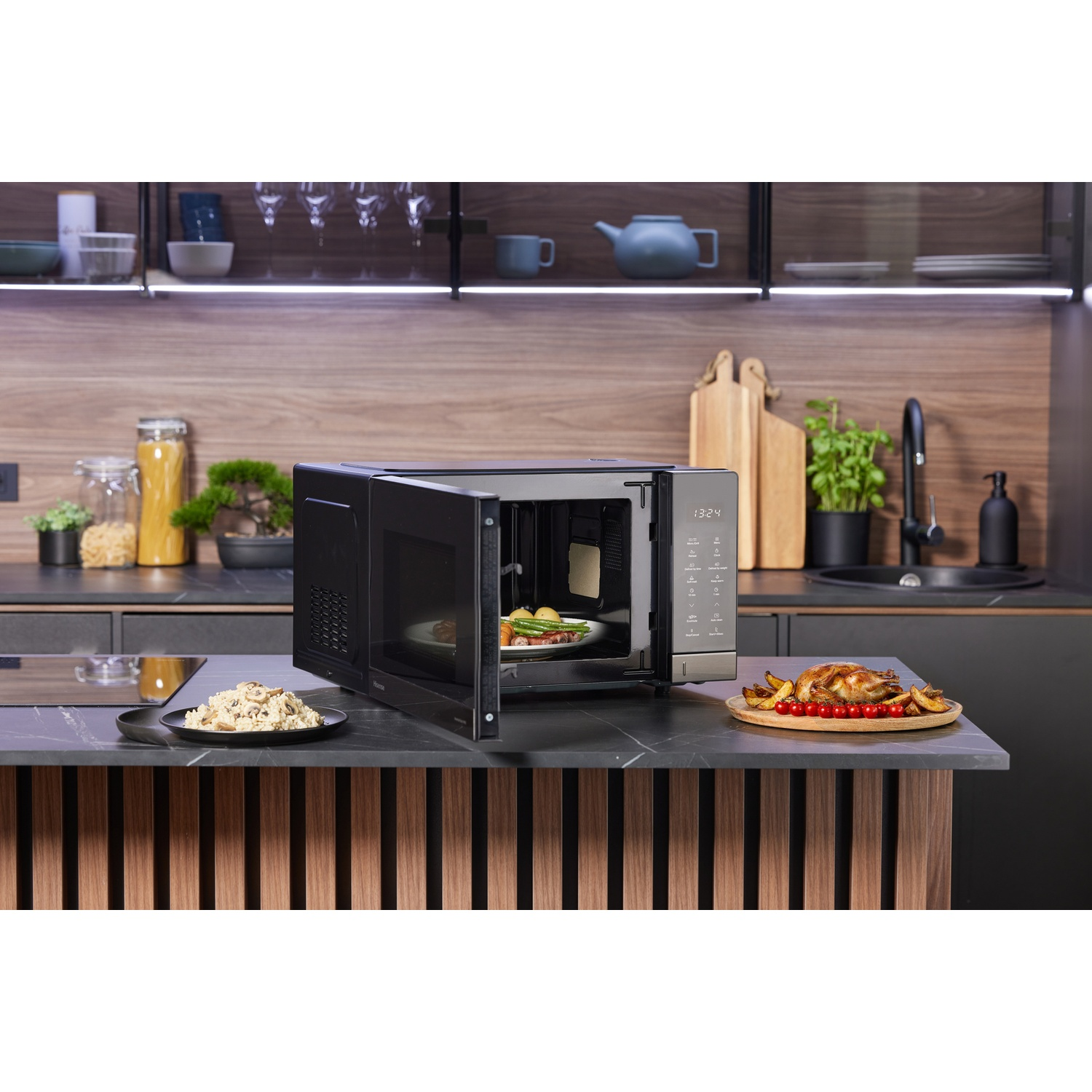 Un forno a microonde nero aperto su un piano di lavoro della cucina con cibo.