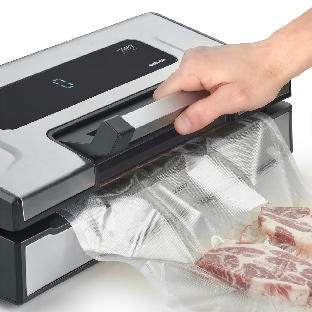 Hand drückt Griff auf Vakuumiergerät. Fleisch in Beutel.