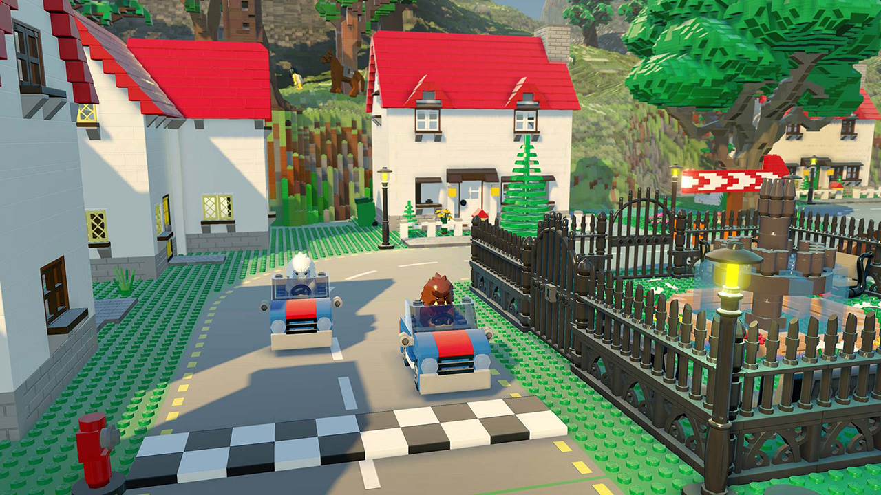 Lego-Stadt mit zwei Autos auf der Straße, Häusern und einem Park mit Zaun.