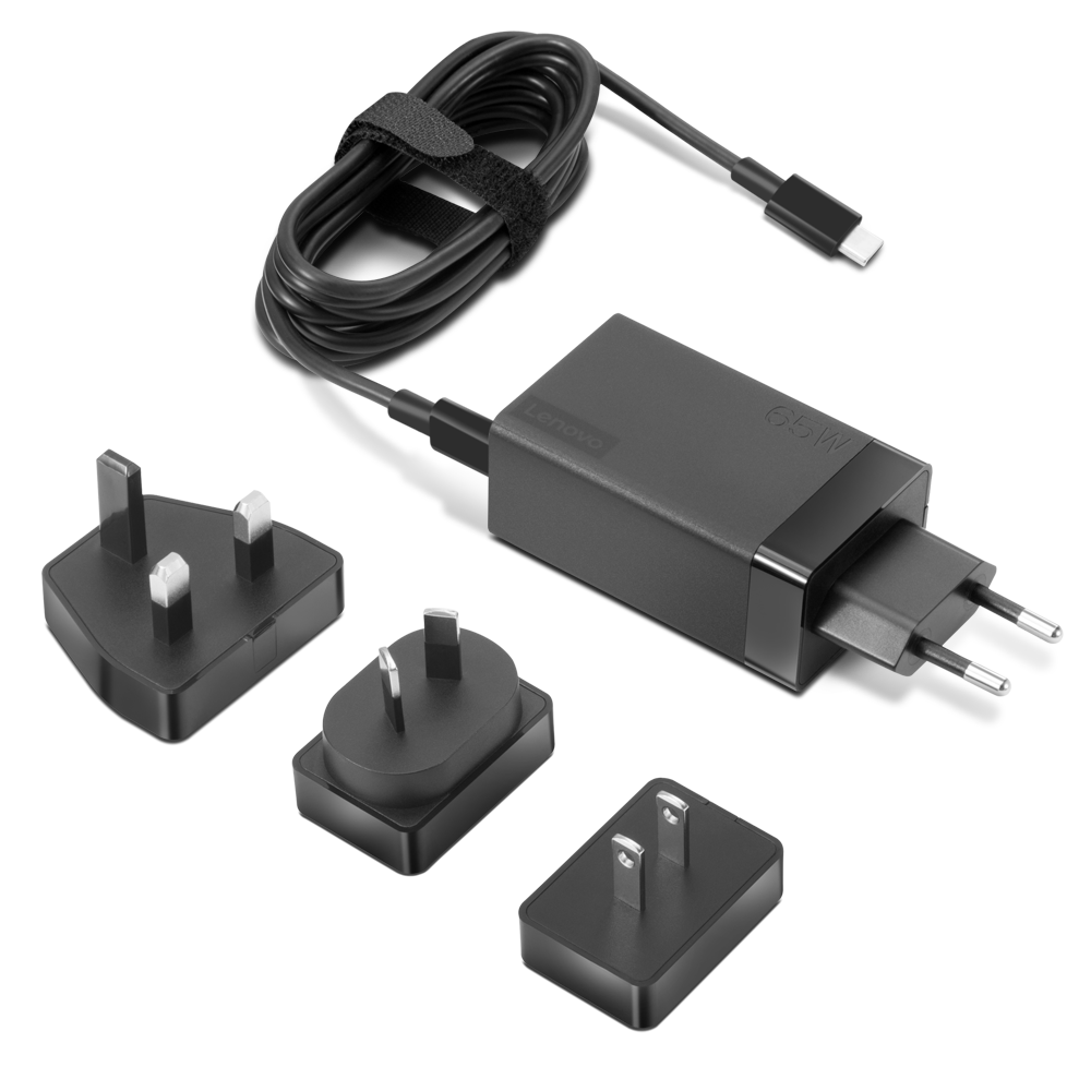 Ein schwarzes Lenovo 65W Ladegerät mit aufgewickeltem Kabel und drei austauschbaren Steckern (UK, EU, US) auf weißem Hintergrund.
