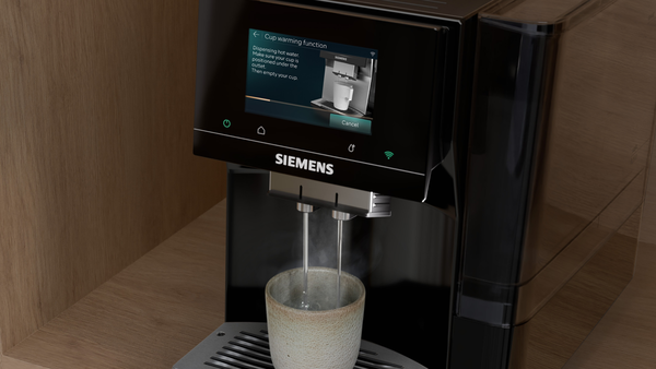 Siemens kahve makinesi fincana sıcak su veriyor. Ekranda fincan ısıtma fonksiyonu gösteriliyor.