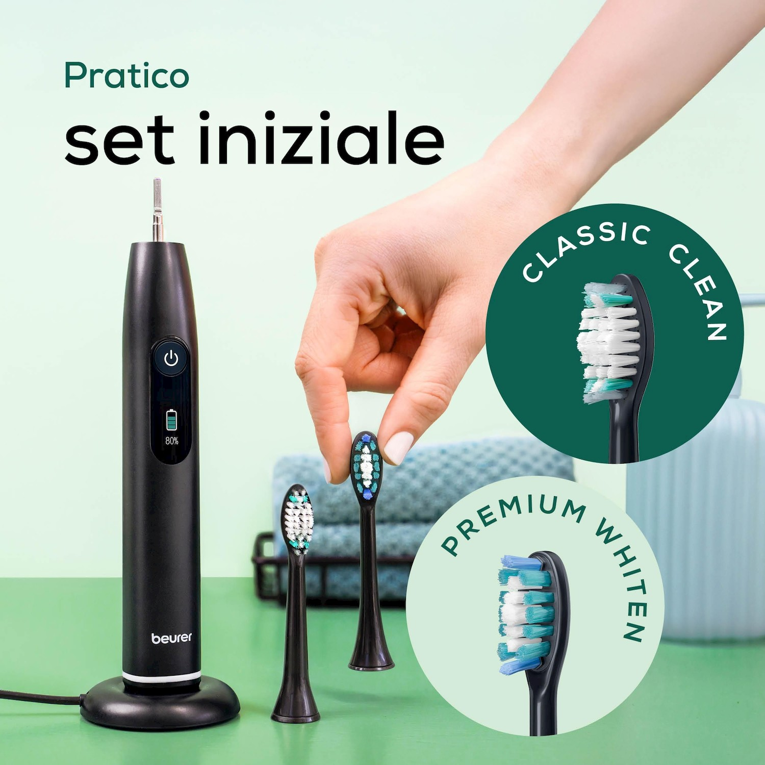 Spazzolino elettrico nero con base di ricarica e tre testine, una mano ne tiene una.