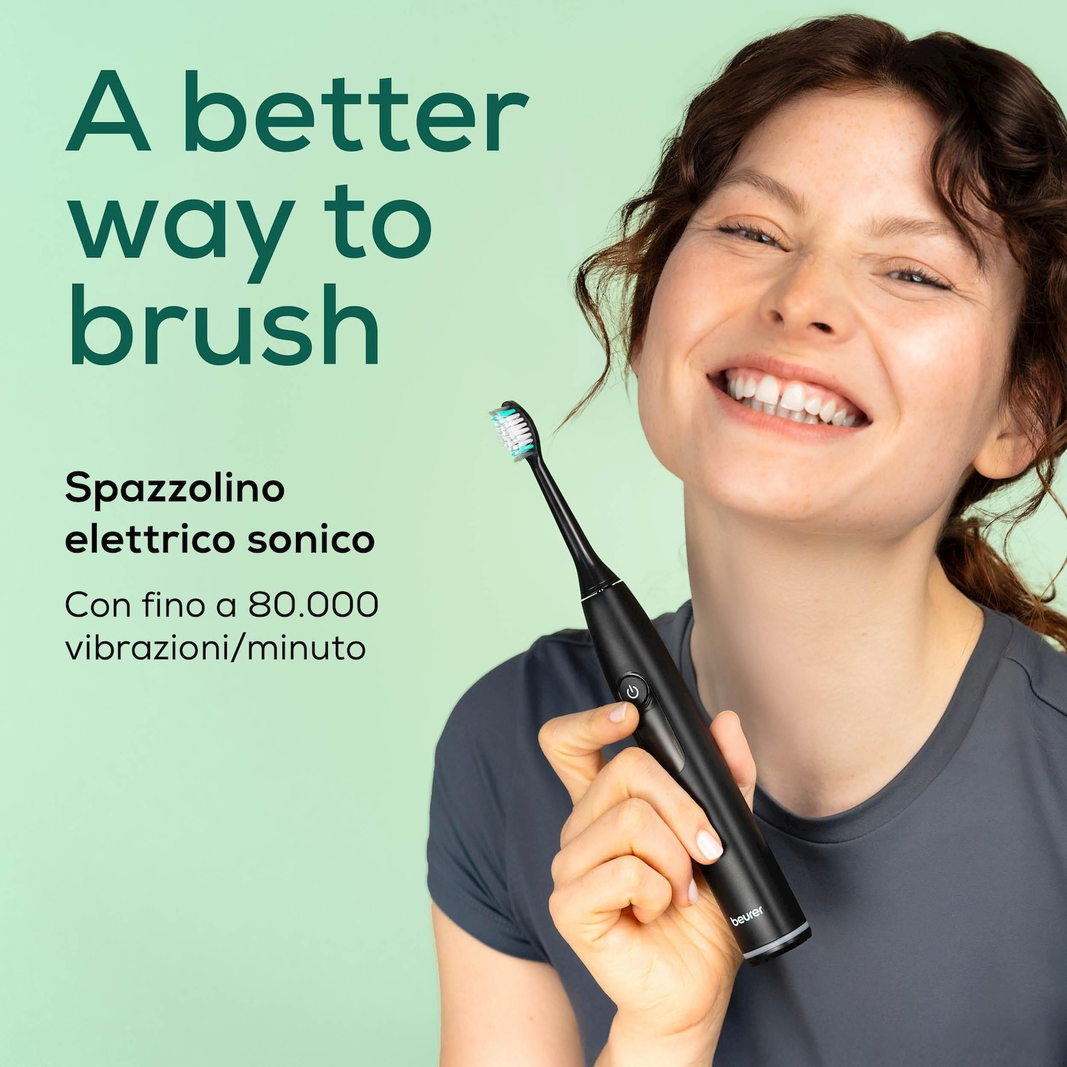 Donna tiene uno spazzolino elettrico sonico nero su sfondo verde chiaro.