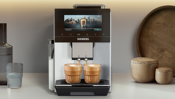 Siemens kahve makinesi iki latte hazırlıyor. Yakında bardak ve şişe var.