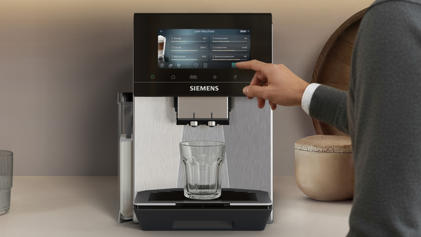 Adam Siemens kahve makinesi dokunmatik ekranını kullanıyor, bardak hazır.