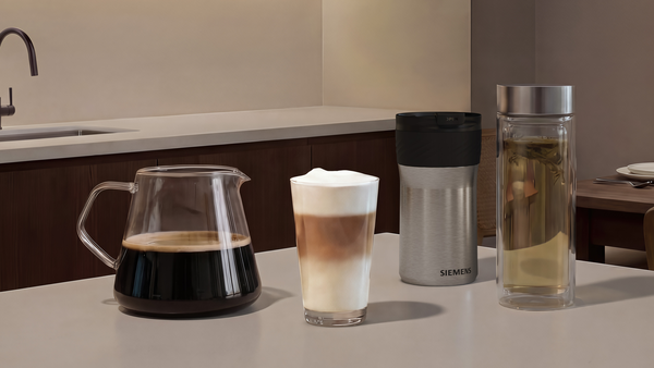 Kahve sürahisi, latte macchiato, termos kupa ve çay bardağı masada.