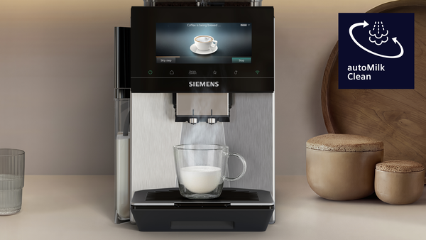Siemens kahve makinesi süt köpürtüyor, cam fincana dolduruyor. Sağda kaplar.
